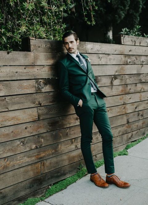 an emerald suit, a black tie and brown shoes and colorful striped socks for a statement fall groom's look