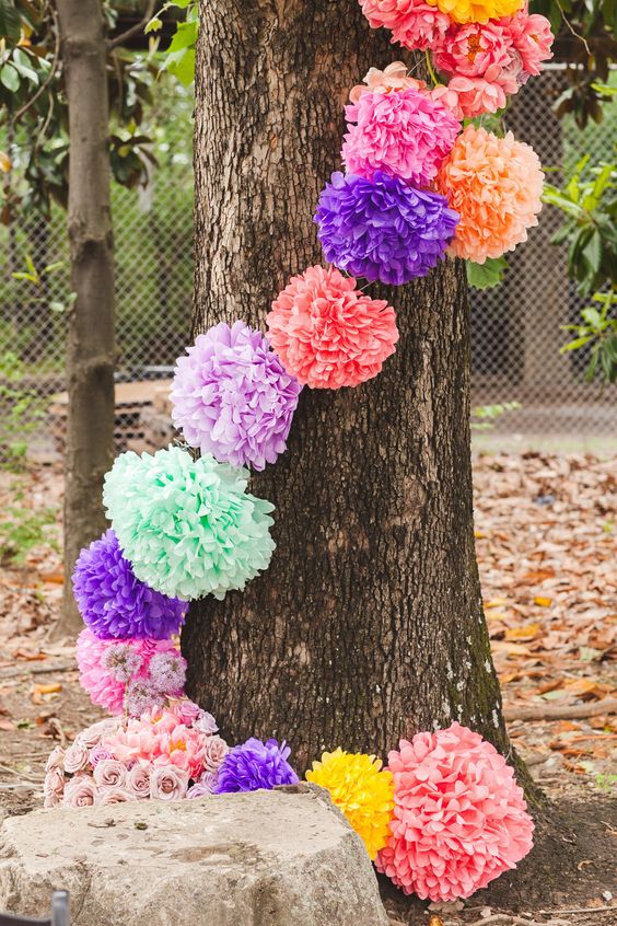 cover trees at the wedding with colorful pompom garland if you want to give the space a festival feel