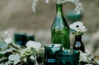 emerald green glasses and a bottle for a centerpiece plus a lush eucalyptus wedding table runner