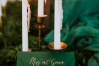 en emerald wedding invitation with gold touches placed in lush ferns on the table