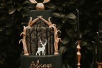 a HarryPotter-themed black wedding cake with gold letters, a Patronus, gold leaves and a gold Snitch cake topper is very dramatic