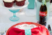 a blue, red and white wedding tablescape with bright plates, cupcakes and Coke in bottles