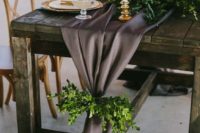 a charcoal grey wedding table runner accented with greenery is a refined and unusual wedding decor idea