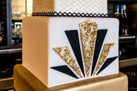 a chic art deco wedding cake with a chevron tier, a white tier with gold glitter and black and a gold tier
