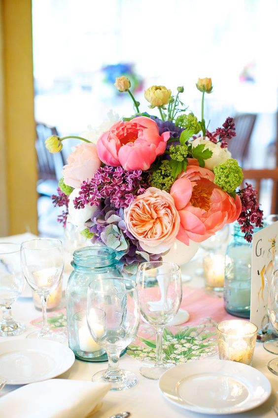 a colorful spring wedding centerpiece in pink, peachy, purple, greenery and with some texture for interest