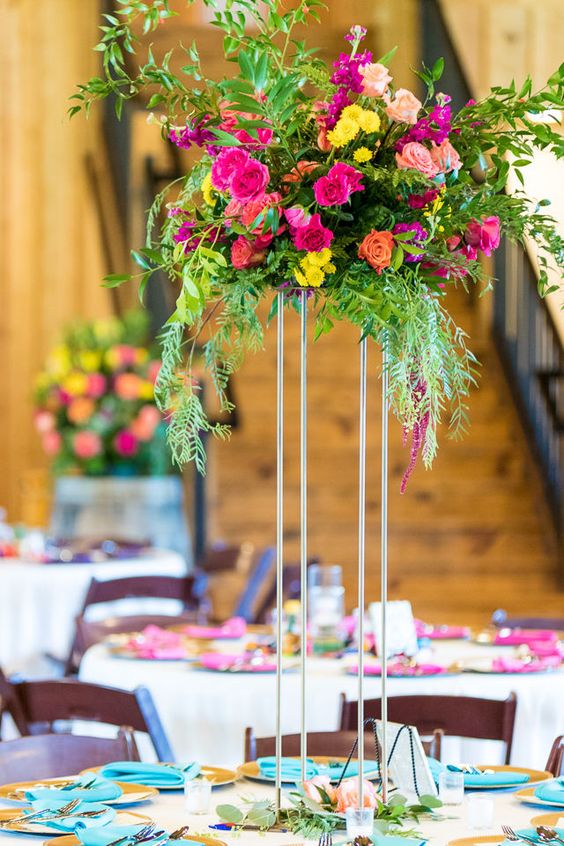 a colorful tall wedding centerpiece in fuchsia, light pink, yellow and some cascading greenery