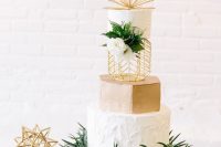a creative modern wedding cake with textural white and a gold tier, greenery and white blooms