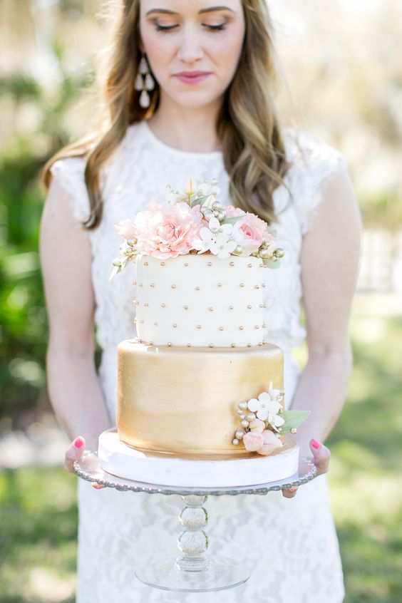 a cute wedding cake with a gold and white and gold polka dot tier and lots of pink and white blooms