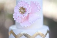 a glam wedding cake with a pink sugar bloom, with gold chevron decor is a stylish idea for a glam wedding in spring or summer