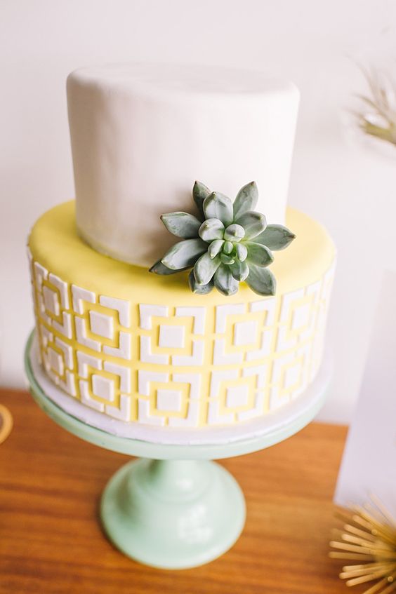 a mid-century inspired wedding cake with a white tier and a geometric yellow one plus a single succulent