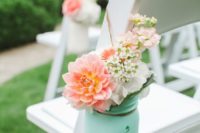 a mint jar with coral and white blooms and greenery to highlight the chairs of your wedding aisle