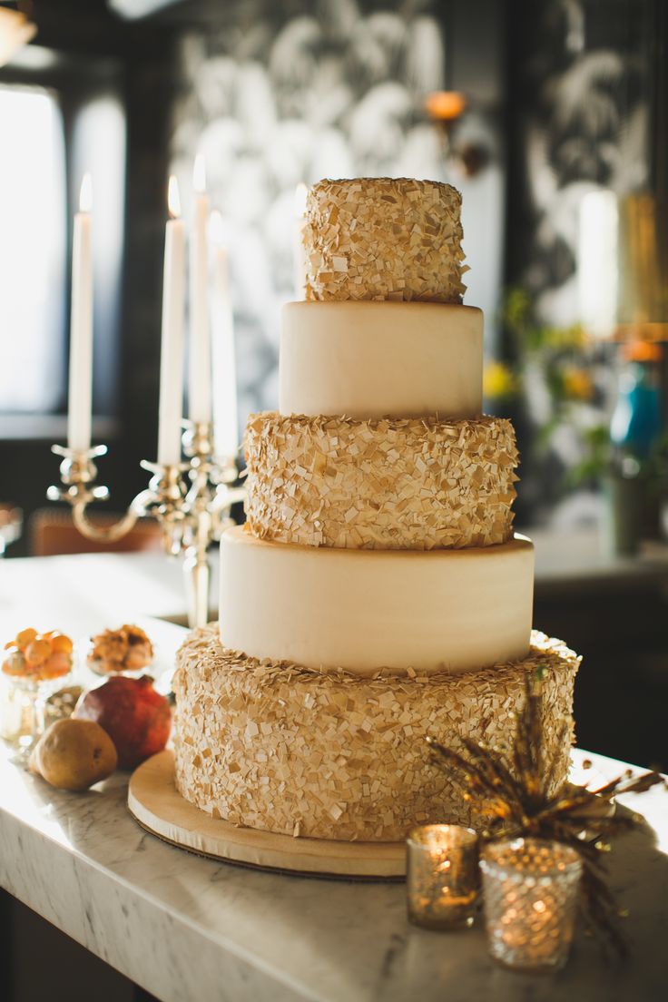 a modern refined wedding cake with white and gold confetti tiers is a chic and refined idea