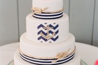 a nautical wedding cake with white tiers, with striped and chevron tiers, gilded rope and pink blooms on top is a great idea to rock