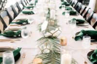 a palm leaf table runner with candles and votives and green napkins that match is a chic tropical idea