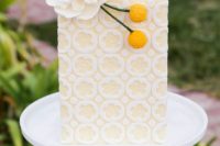 a pastel yellow and white patterned wedding cake decorated with a sugar flower and billy balls