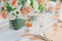 a pretty mint, coral and white wedding tablescape with a floral centerpiece, twigs and peach lemonade
