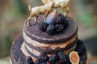 a pretty woodland naked wedding cake topped with blackberries, figs and cute gilded deer symbolizing the couple is amazing
