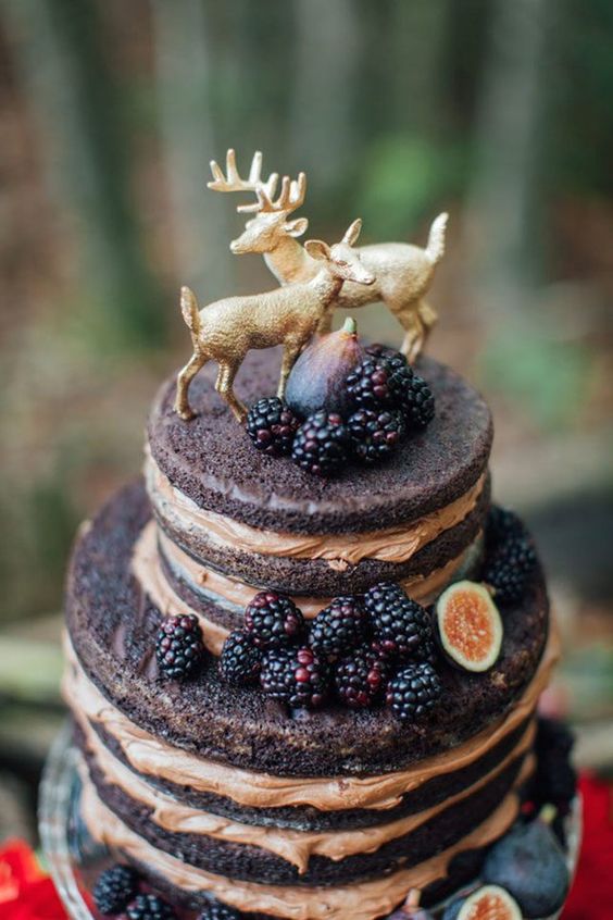 a pretty woodland naked wedding cake topped with blackberries, figs and cute gilded deer symbolizing the couple is amazing