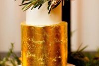 a refined fall wedding cake with a white and gold leaf tier with gilded blooms and greenery on top