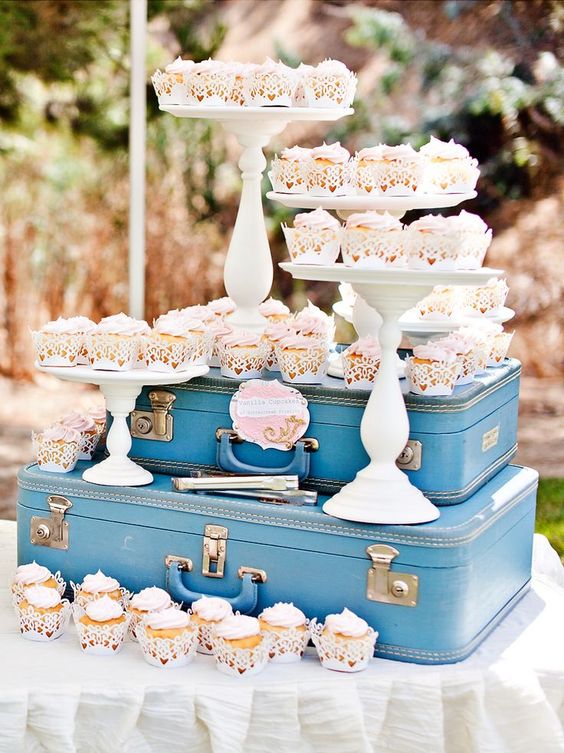 a retro-inspired dessert bar with blue suitcases and cupcakes on stands is a gorgeous idea for a retro wedding