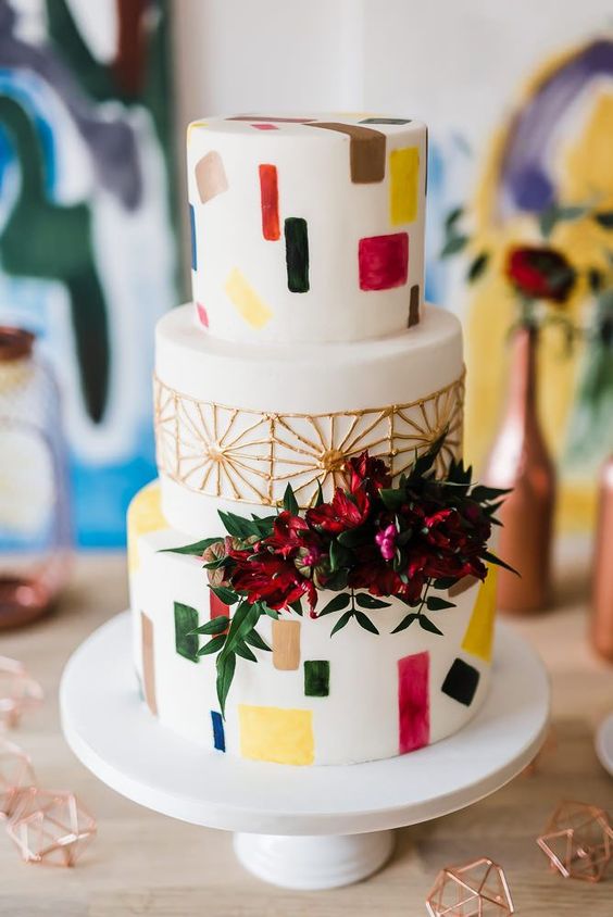 a retro wedding cake with terrazzo patterns, gold detailing and bright blooms