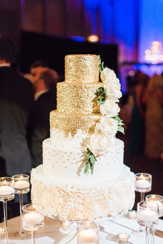 a romantic wedding cake with gold polka dot tiers and a white floral one, with sugar blooms and leaves