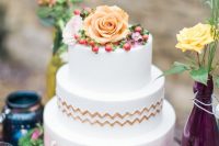 a round wedding cake with white and watercolor pink tiers, gold chevrons, fresh blooms and berries is a lovely idea for a wedding