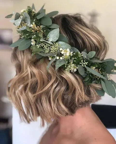 a short wavy blonde bob styled with a greenery and white flower crown is a very cool and fresh idea for a wedding