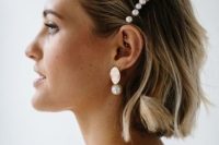 a short wavy bob with balayage and with a pearl hair barrette and matching earrings