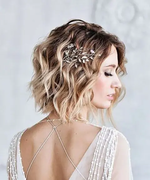 a short wavy bob with blonde balayage and a delicate and chic botanical hairpiece is a beautiful idea