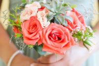 a small wedding bouquet with coral and blush blooms, greenery and succulents is very chic