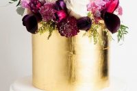 a sophisticated wedding cake with white and gold leaf tiers and purple, fuchsia and pink blooms and greenery