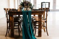 a teal fabric table runner, black candles, gold touches and greenery will make the tablescape moody and chic