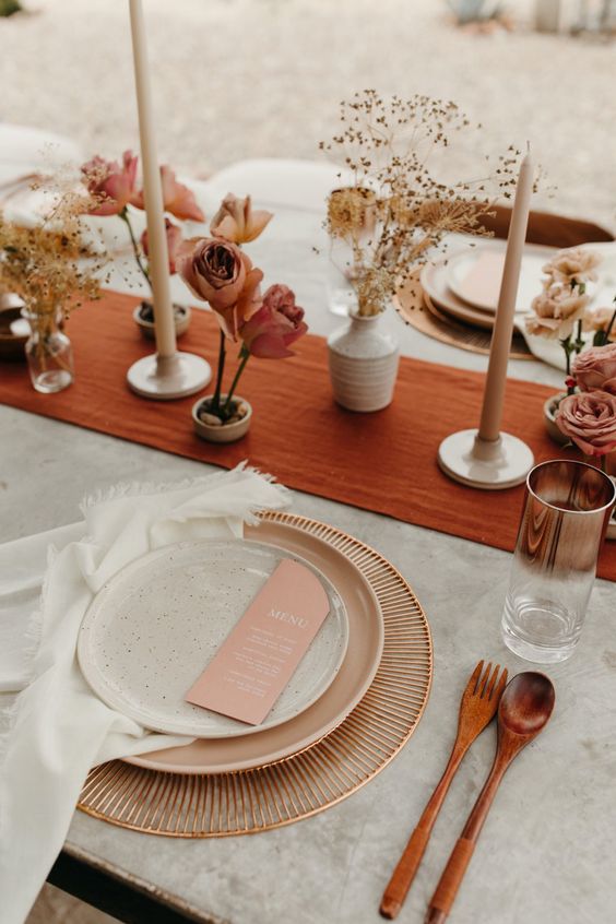 a terracotta fabric table runner paired with dried herbs and blooms, copper touches and wooden cutlery
