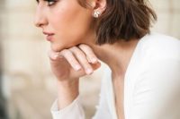 a textural short bob with balayage and a white rhinestone hair barrette and matching earrings