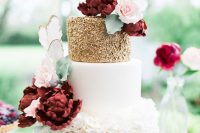 a very romantic and chic wedding cake with a sleek white, gold polka dot and white floral tier and lots of sugar blooms in burgundy and blush