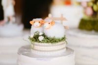 a white buttercream wedding cake with a unique cake topper – a couple of sheer on green grass is very cute and very lovely