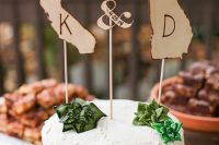 a white buttercream wedding cake with sugar succulents and plywood statement silhouettes that show where the couple comes from