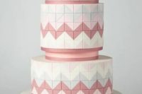 a white, pink and grey wedding cake with squares covering its surface and chevron patterns for more eye-catchiness