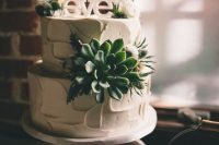 a white textural buttercream wedding cake decorated with a succulent, thistles and white blooms plus a white cake topper is amazing