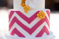 a white wedding cake with fuchsia chevrons, white and mustard sugar blooms on top is a lovely idea for a bright wedding