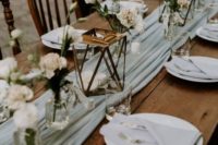 an aqua fabric table runner and neutral linens and blooms create a fresh and romantic spring wedding tablescape