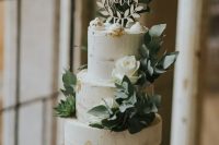 an elegant naked rustic wedding cake with gold leaf, leaves, white roses, meringues and a plywood wreath cake topper is a very cool idea