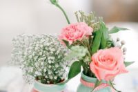 mint and coral jars with baby’s breath, coral blooms and greenery to compose a cool wedding centerpiece