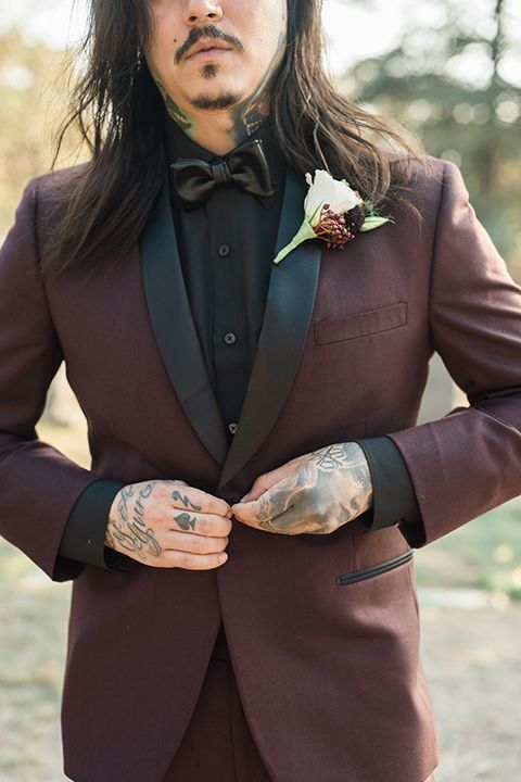 a Halloween groom's look with a black shirt and a leather bow tie, a burgundy tux with black lapels