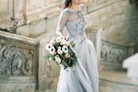 a beautiful light grey wedding dress with an embroidered illusion bodice, long sleeves and a layered skirt plus a train