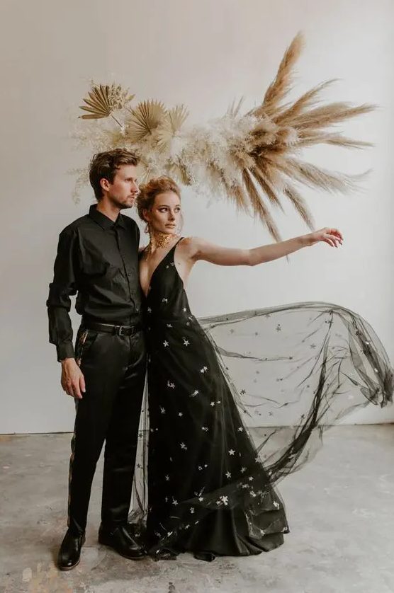 a black A-line wedding dress with a plunging neckline, straps and silver stars all over the gown is a bold and statement idea to try