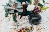 a boho wedding centerpiece with succulents in vases, a vase with blooms and a feather