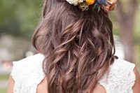 a braided wavy half updo with a bold floral hairpiece to embrace the season is a lovely idea for a destination wedding