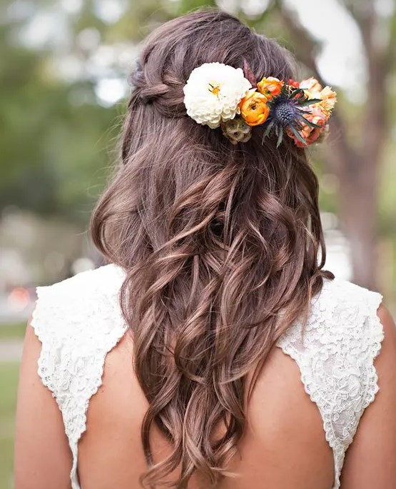 a braided wavy half updo with a bold floral hairpiece to embrace the season is a lovely idea for a destination wedding
